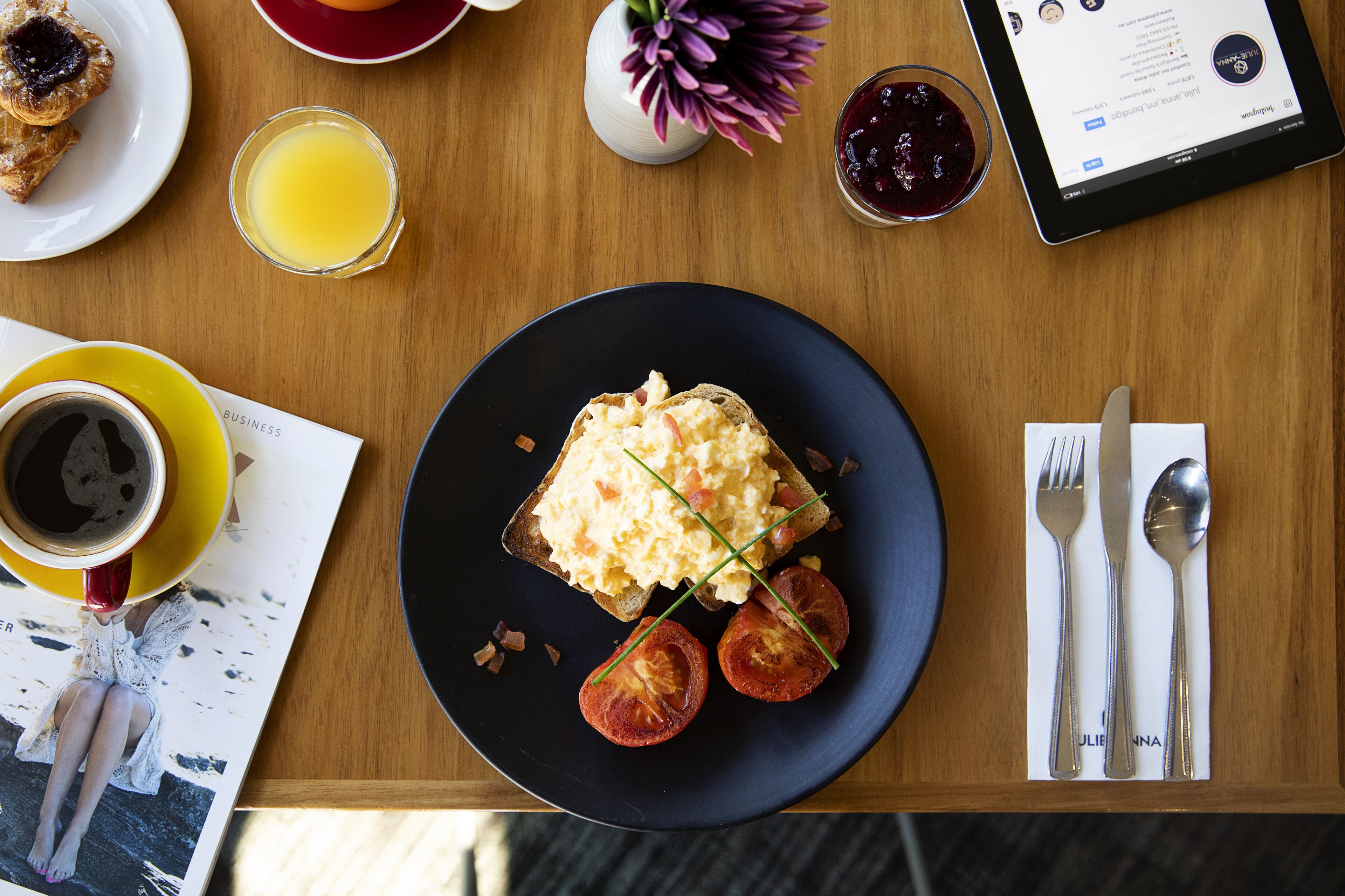 A breakfast table with toast, tomatoes, and a cup of coffee.
