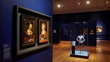 En museiinteriör med inramade konstverk och ett vitrinskåp.