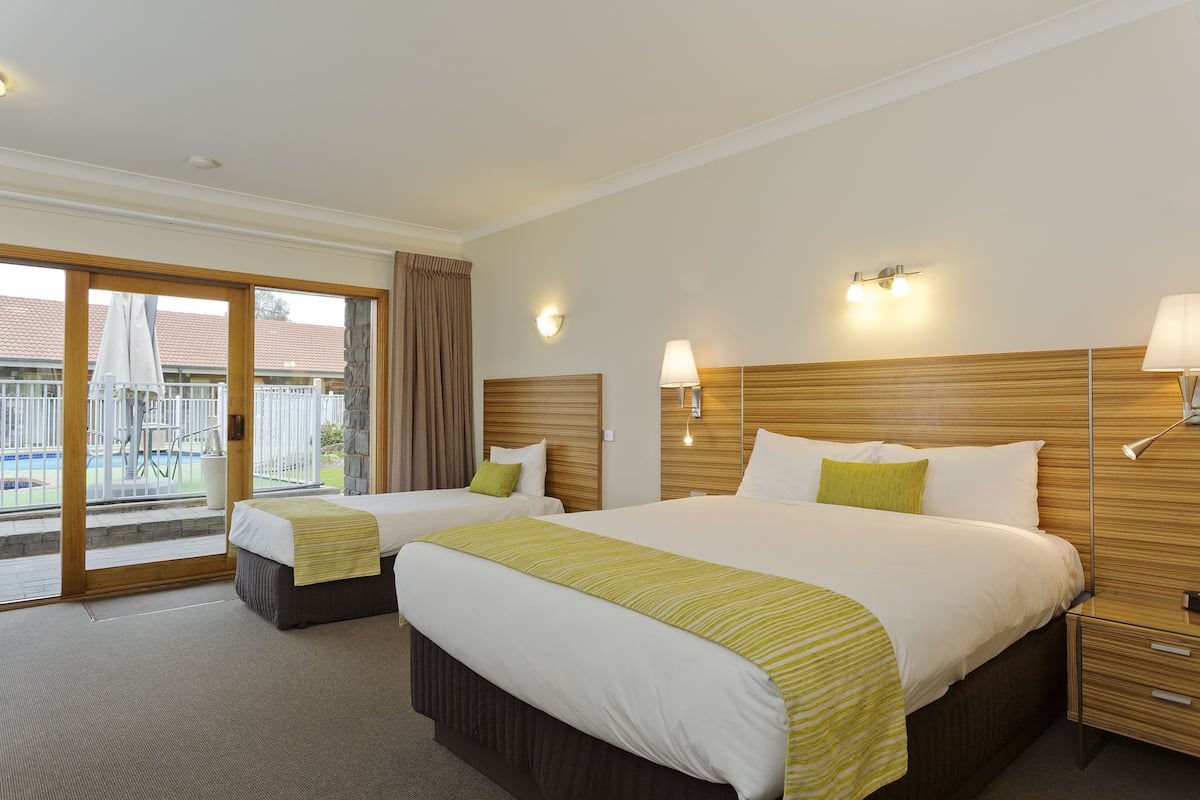 A hotel room with two beds, a balcony with a view, and a wooden headboard.