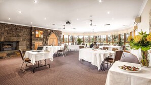 A conference room with round tables, a stone wall, and a fireplace. - Julie-Anna Inn, Bendigo (Bendigo)