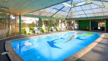 Una piscina techada, una piscina al aire libre, sombrillas