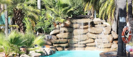 Una piscina techada, una piscina al aire libre, sombrillas