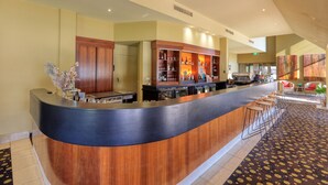 Zona de bar con mostrador de madera, estantes con botellas y una máquina de café.