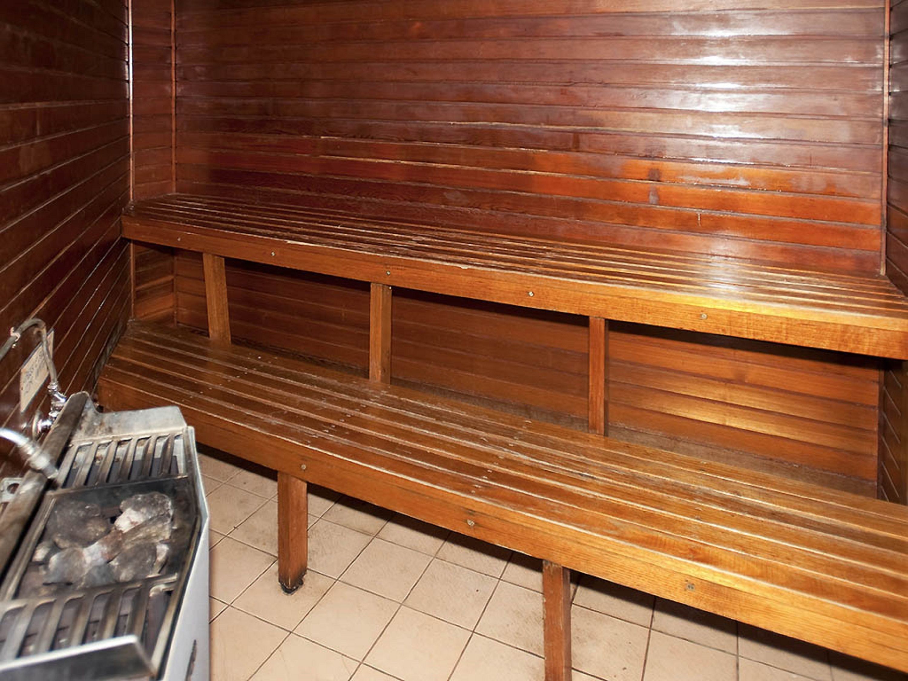 A wooden bench in a room with tiled flooring and wooden walls.