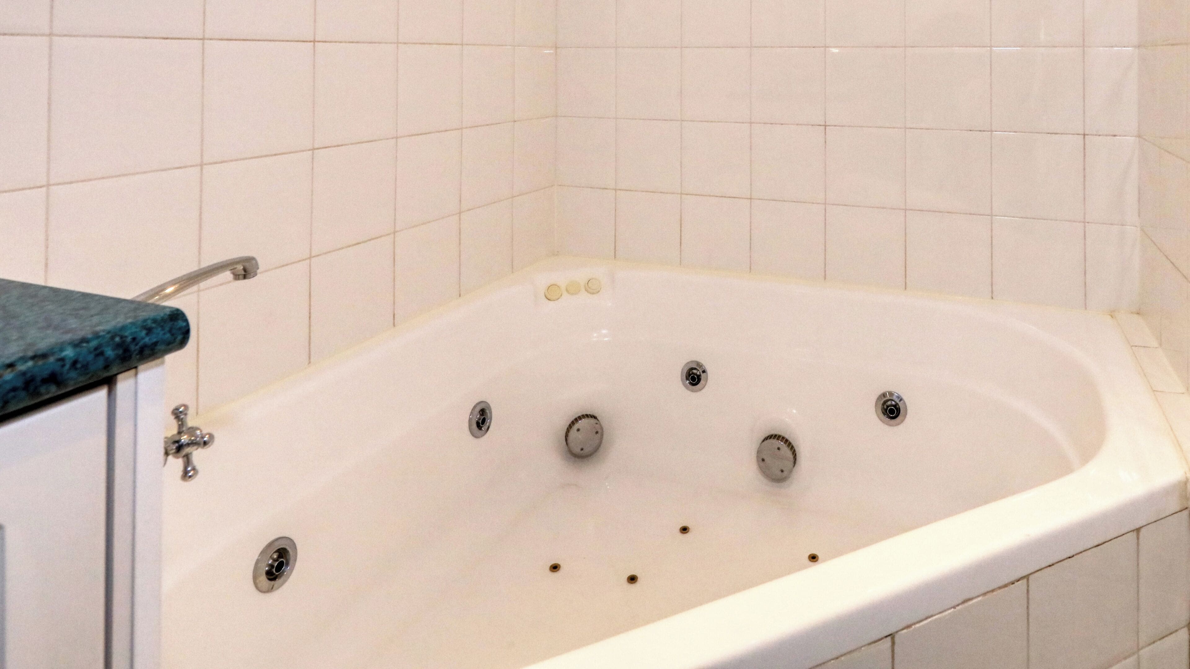 A white bathtub with multiple drain holes, a faucet, and a control panel with buttons.