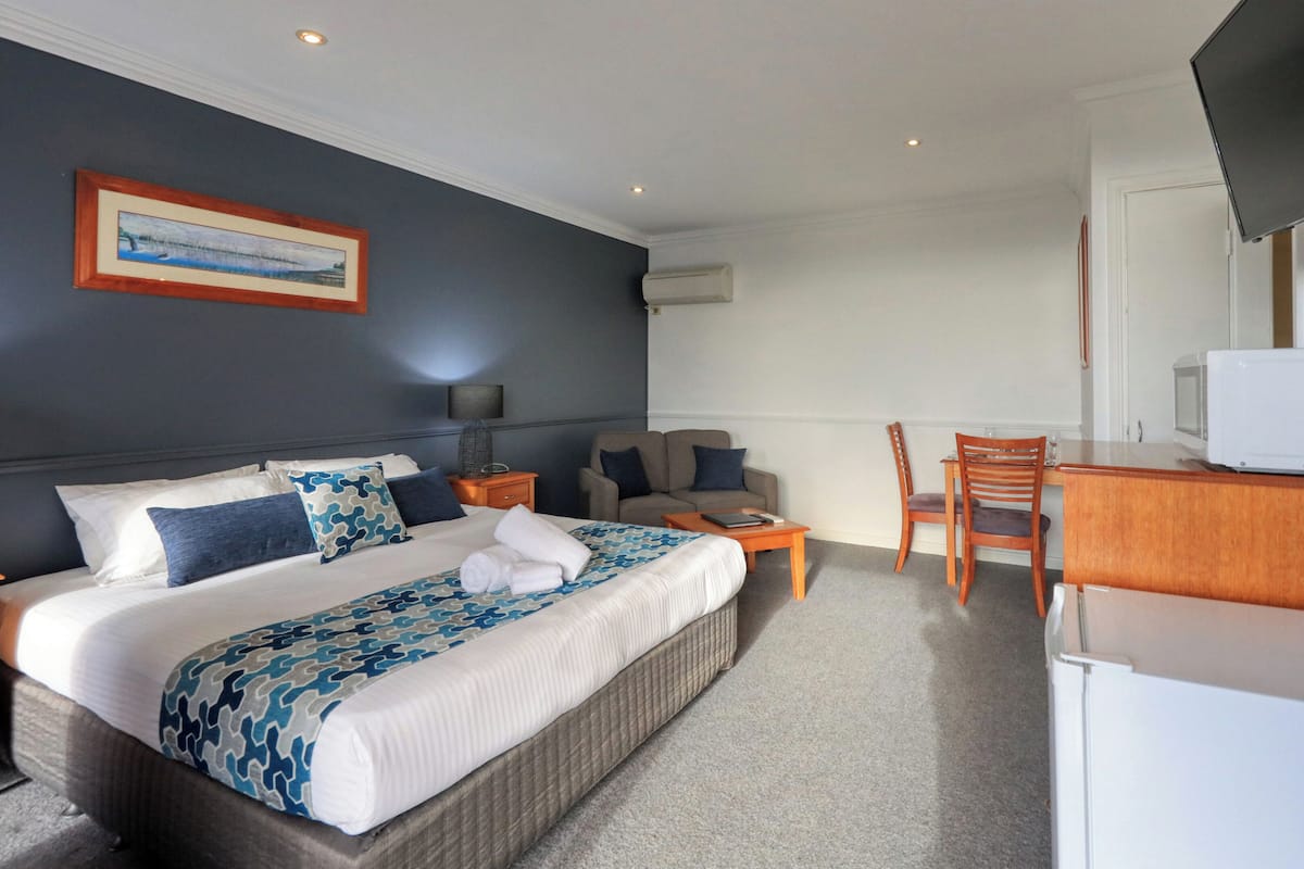 Une chambre d’hôtel avec un grand lit, un bureau, une chaise, une télévision et un tableau encadré au mur.