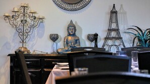 A Buddha statue, a candelabra, and a model of the Eiffel Tower on a table. - Hilltop Motel (Broken Hill)