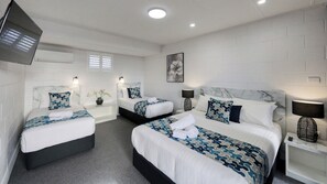 Two single beds with matching headboards and footboards, each with a decorative pillow and bedside table with a lamp.