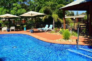 Una piscina al aire libre, sillones reclinables de piscina