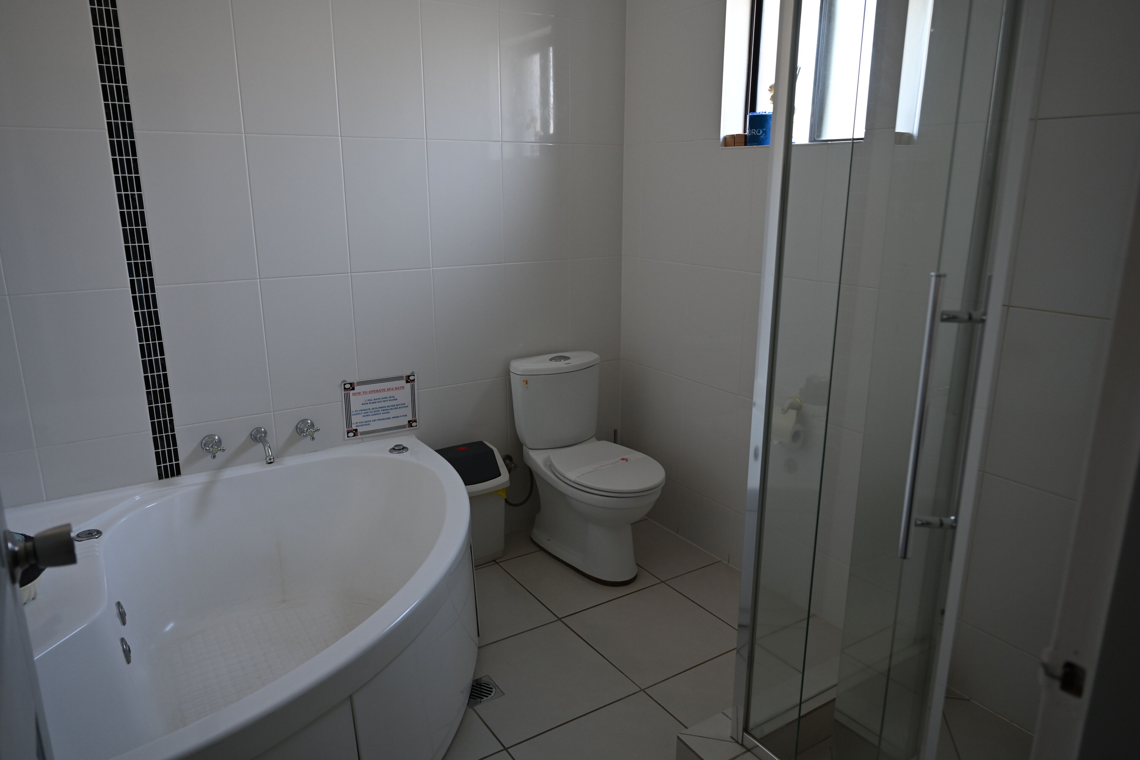 A bathroom with a large bathtub, toilet, and glass shower enclosure.