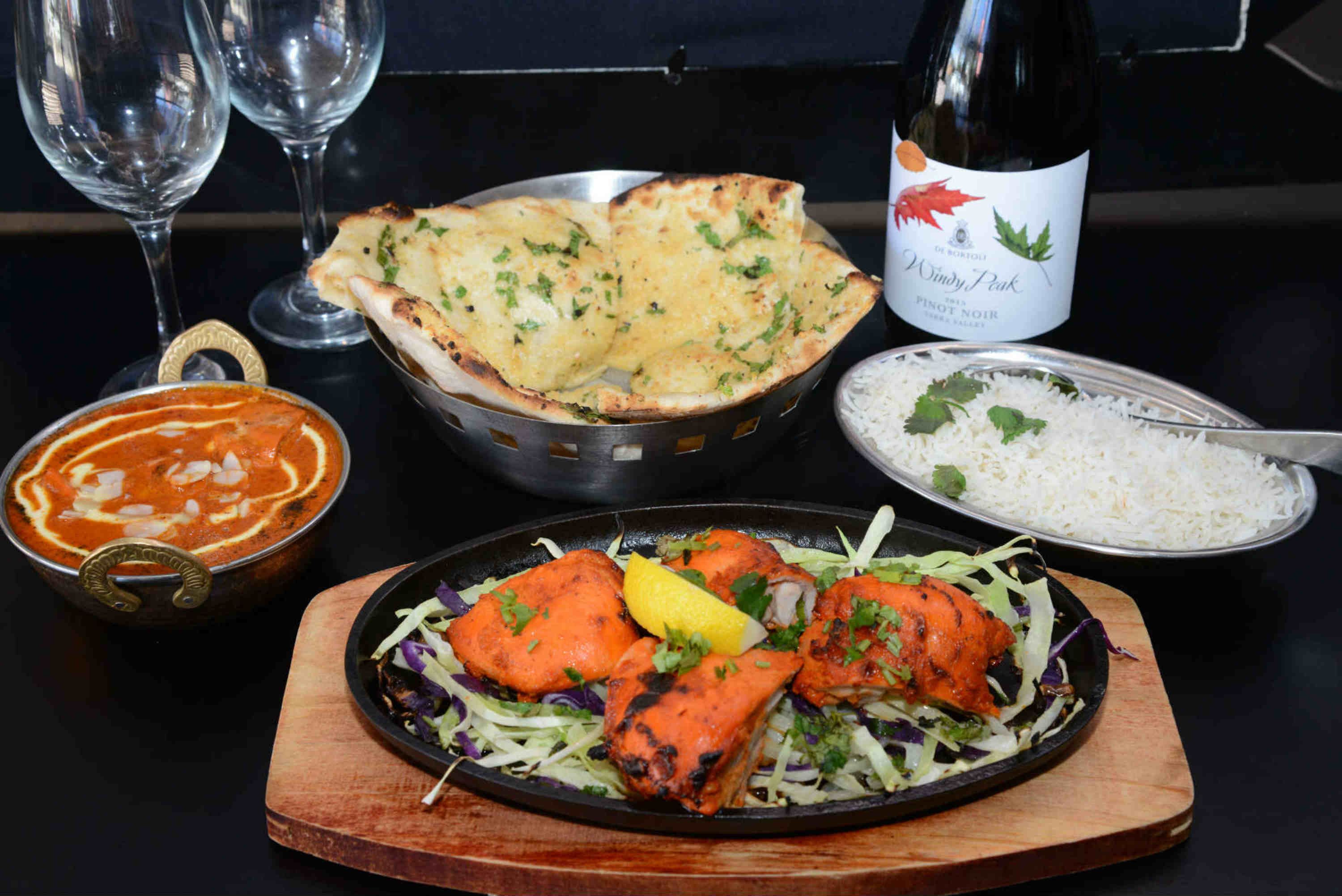 A meal with tandoori chicken, naan bread, and a bowl of rice.