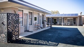 A modern building with numbered doors, outdoor seating, and solar panels. - Cameo Inn Motel (West Wyalong)