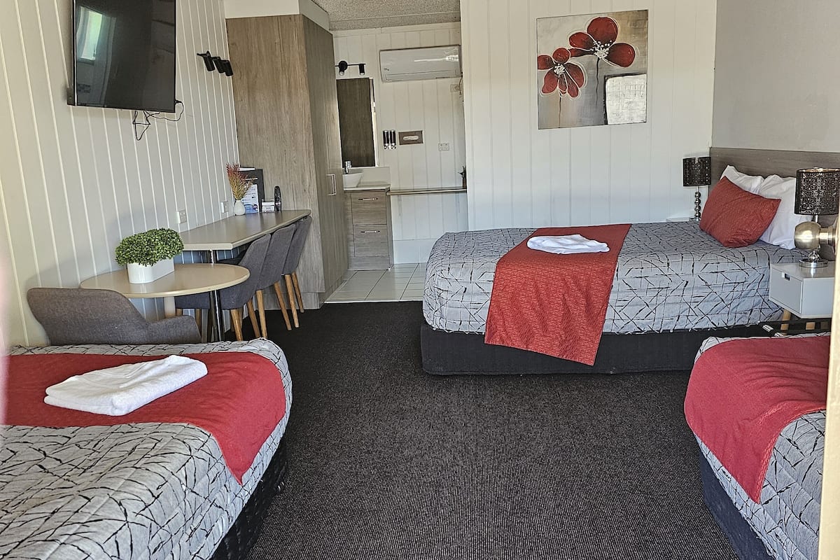 Ett hotellrum med två sängar, ett skrivbord, en stol, en TV och ett badrum.