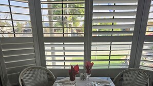 A dining table with two wicker chairs, set for two with wine glasses and red roses. - Cameo Inn Motel (West Wyalong)