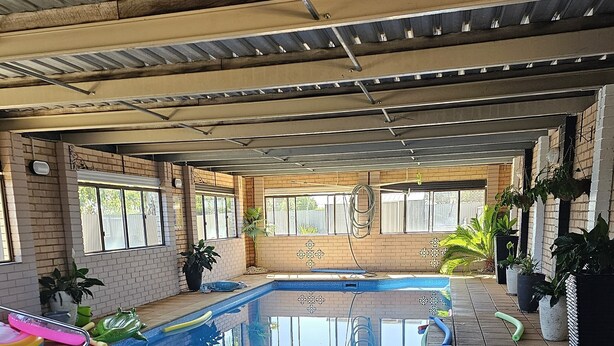 An indoor swimming pool area with tiled flooring, a pool with blue and white tiles, and a 'Cameno Inn' sign. - Cameo Inn Motel (West Wyalong)