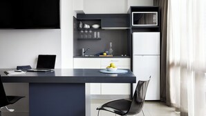 Een moderne keuken met een donker aanrecht, een laptop, een schaal met citroenen en een koelkast.