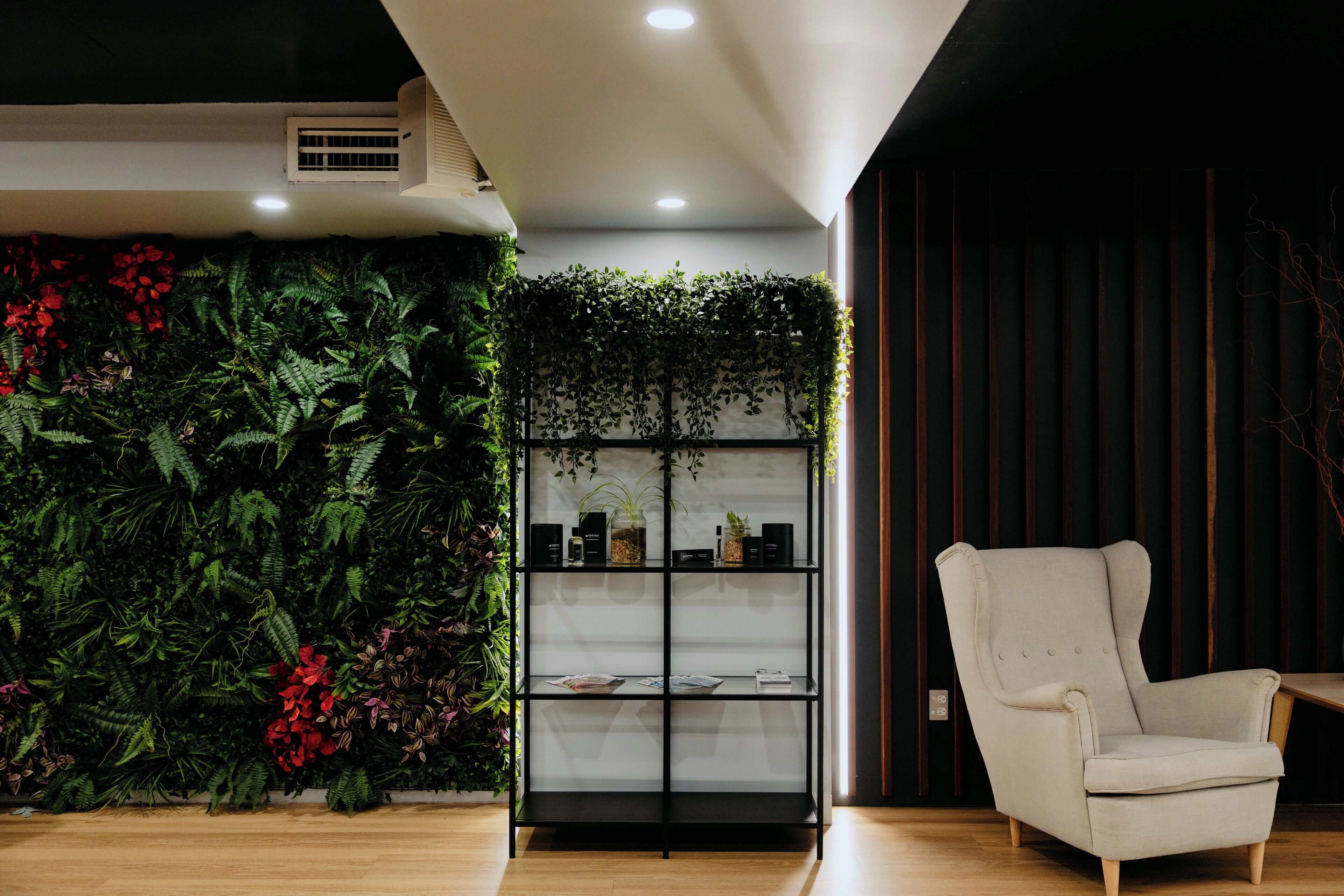 A room with a vertical garden, a bookshelf, and a light-colored armchair.