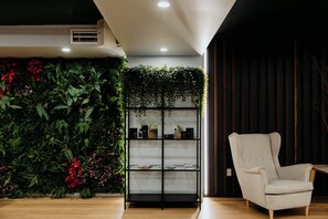 A room with a vertical garden, a bookshelf, and a light-colored armchair. - Punthill Spring Hill (Spring Hill)