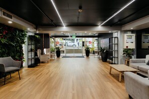 A modern interior with a reception desk, seating area, and a view of the street. - Punthill Spring Hill (Spring Hill)