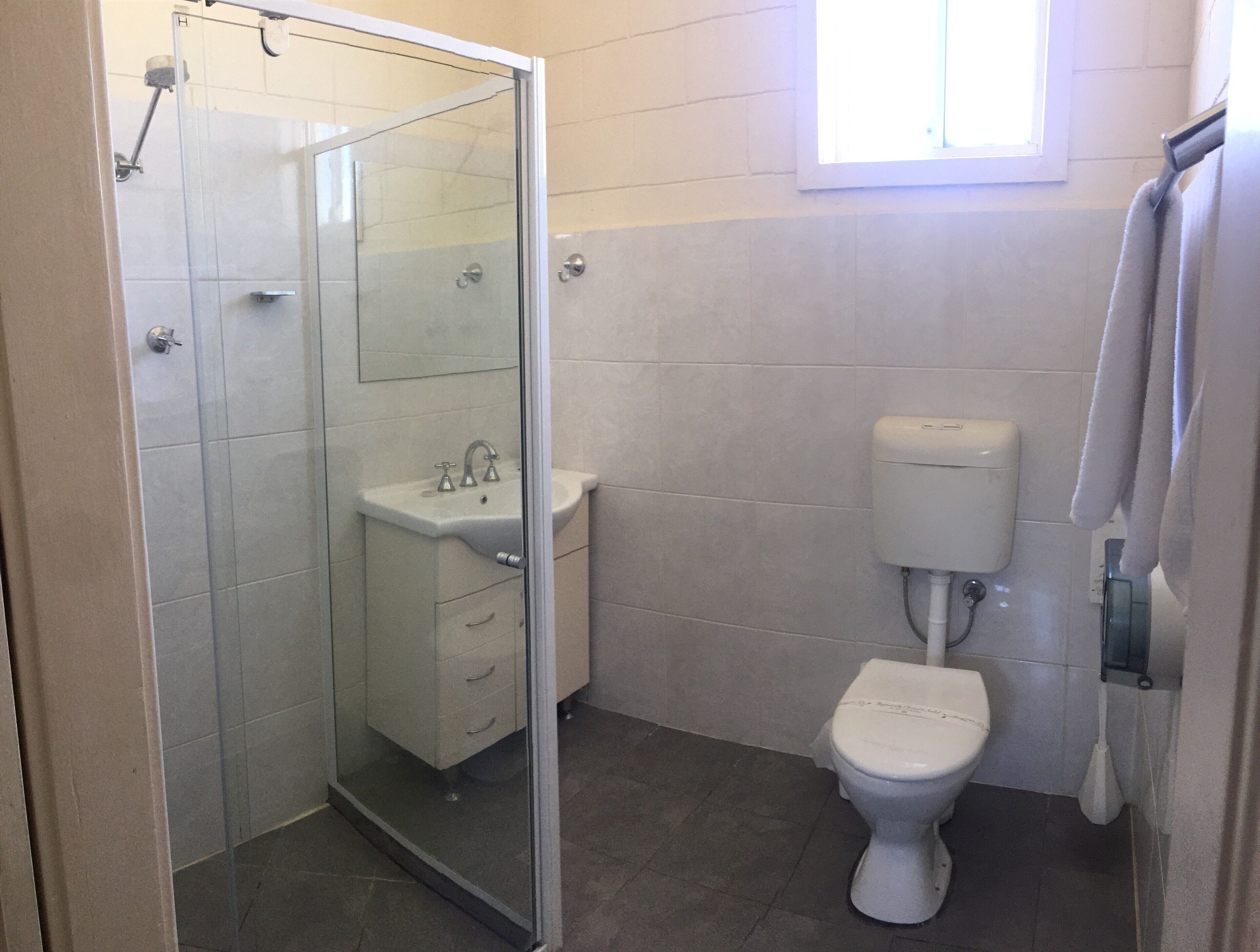 Un baño con cabina de ducha de vidrio, lavamanos e inodoro.