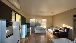 A compact living space with a kitchenette, a dining area, and a seating area with a sofa and a chair. - Ceduna East West Motel (Ceduna)
