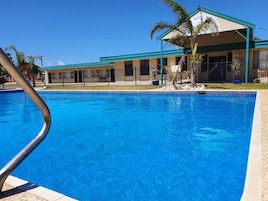 Una piscina al aire libre, sombrillas, sillones reclinables de piscina