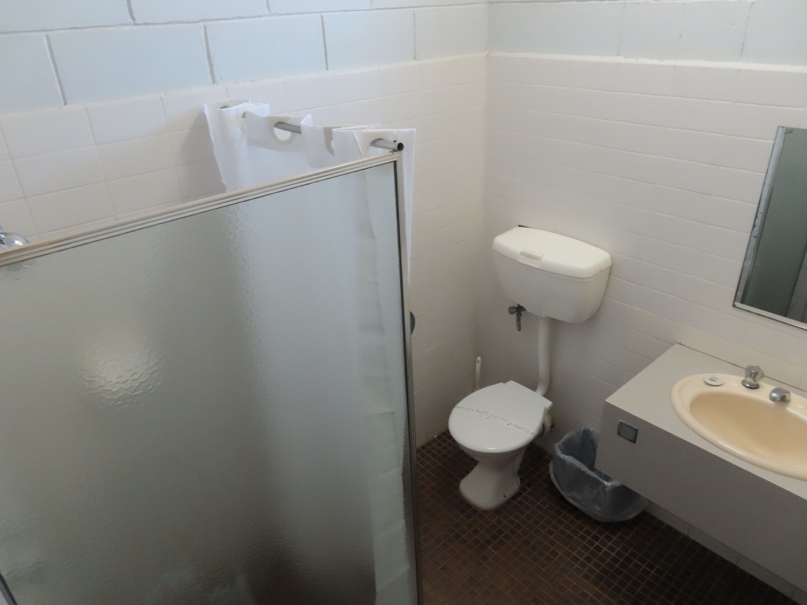 A bathroom with a toilet, sink, and a glass shower enclosure.
