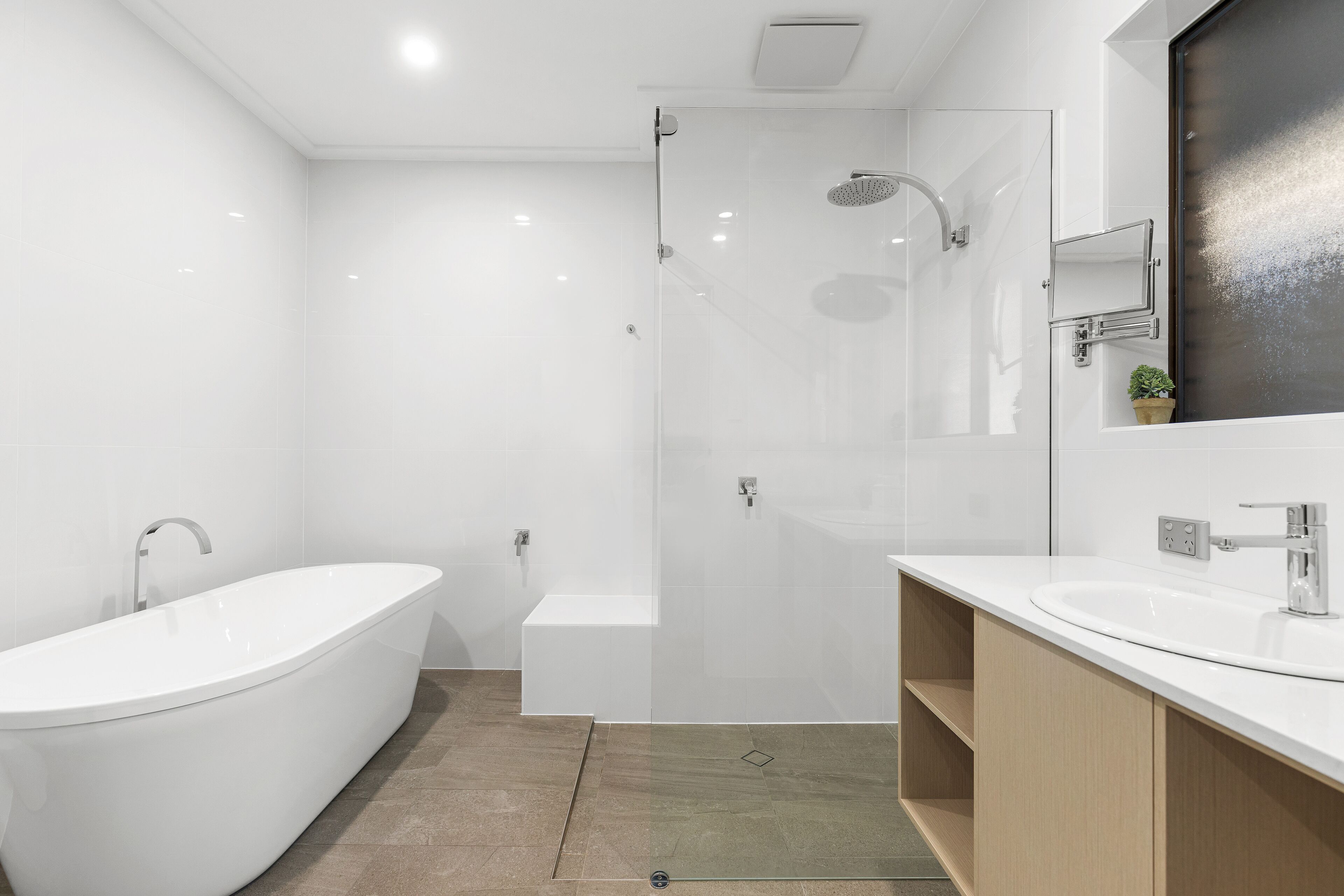 A modern bathroom with a freestanding bathtub, a glass-enclosed shower, and a vanity with a mirror.