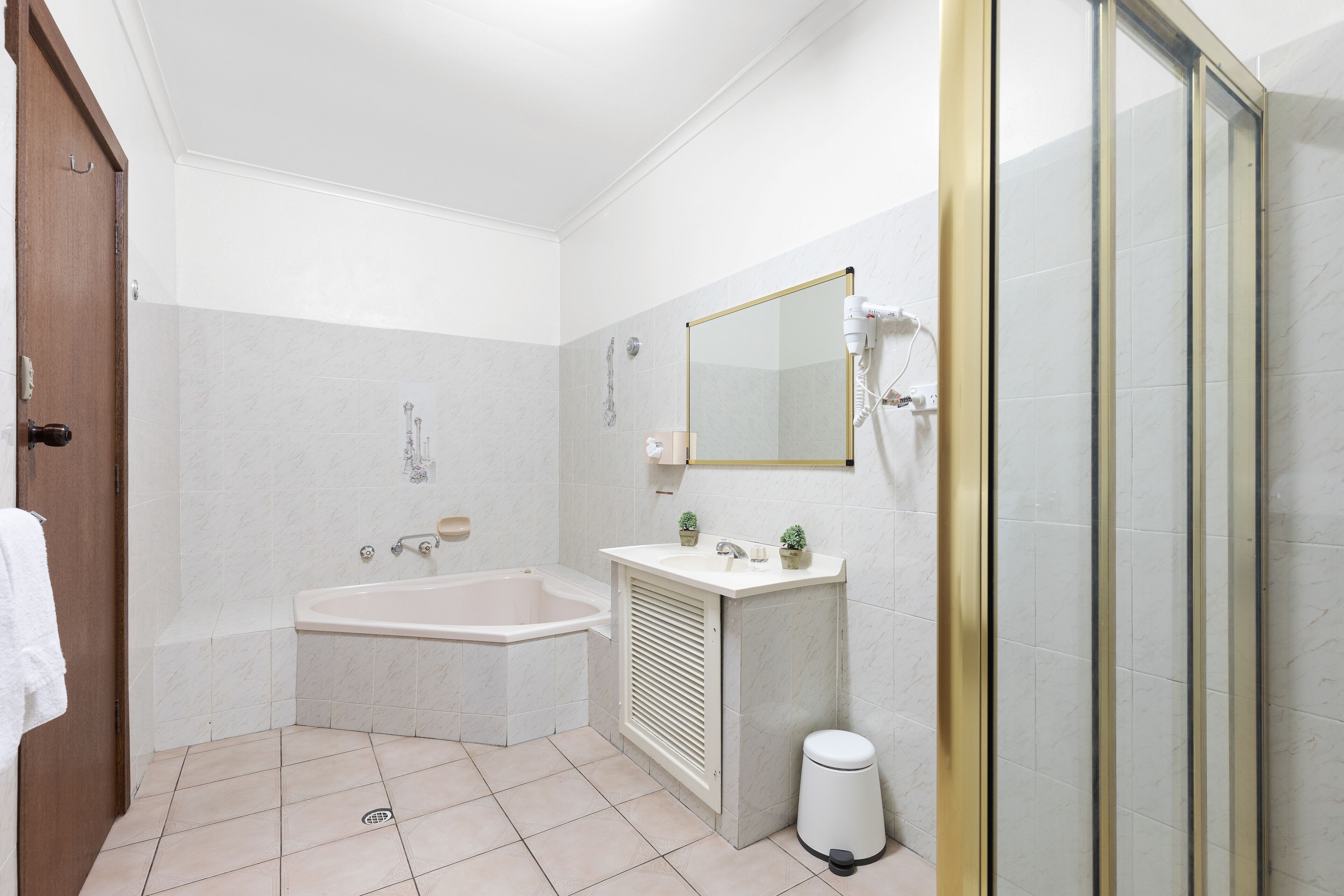 A bathroom with a bathtub, a sink, a mirror, and a shower area.