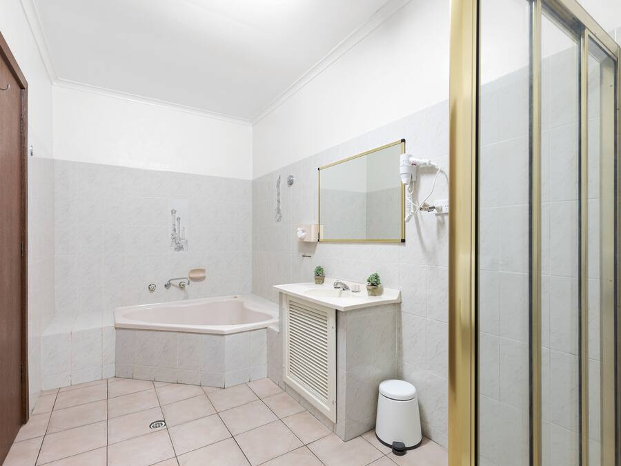 Ein Badezimmer mit Badewanne, Waschbecken, Spiegel und Duschbereich.