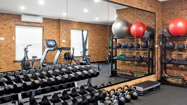 A gym with exercise equipment, a treadmill, and a mirrored wall. - Presidential Motel (Mount Gambier)