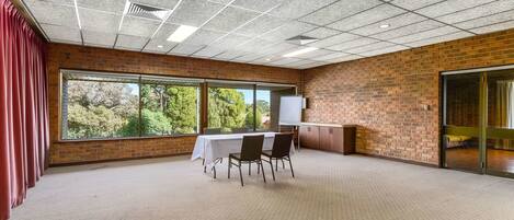 A conference room with a brick wall, large windows, a whiteboard, and a carpeted floor.