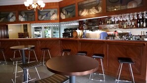 A bar area with wooden paneling, multiple stools, a bar counter, and a variety of bottles and glasses. - Mercure Port of Echuca (Echuca)