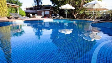 Una piscina al aire libre, sombrillas, sillones reclinables de piscina