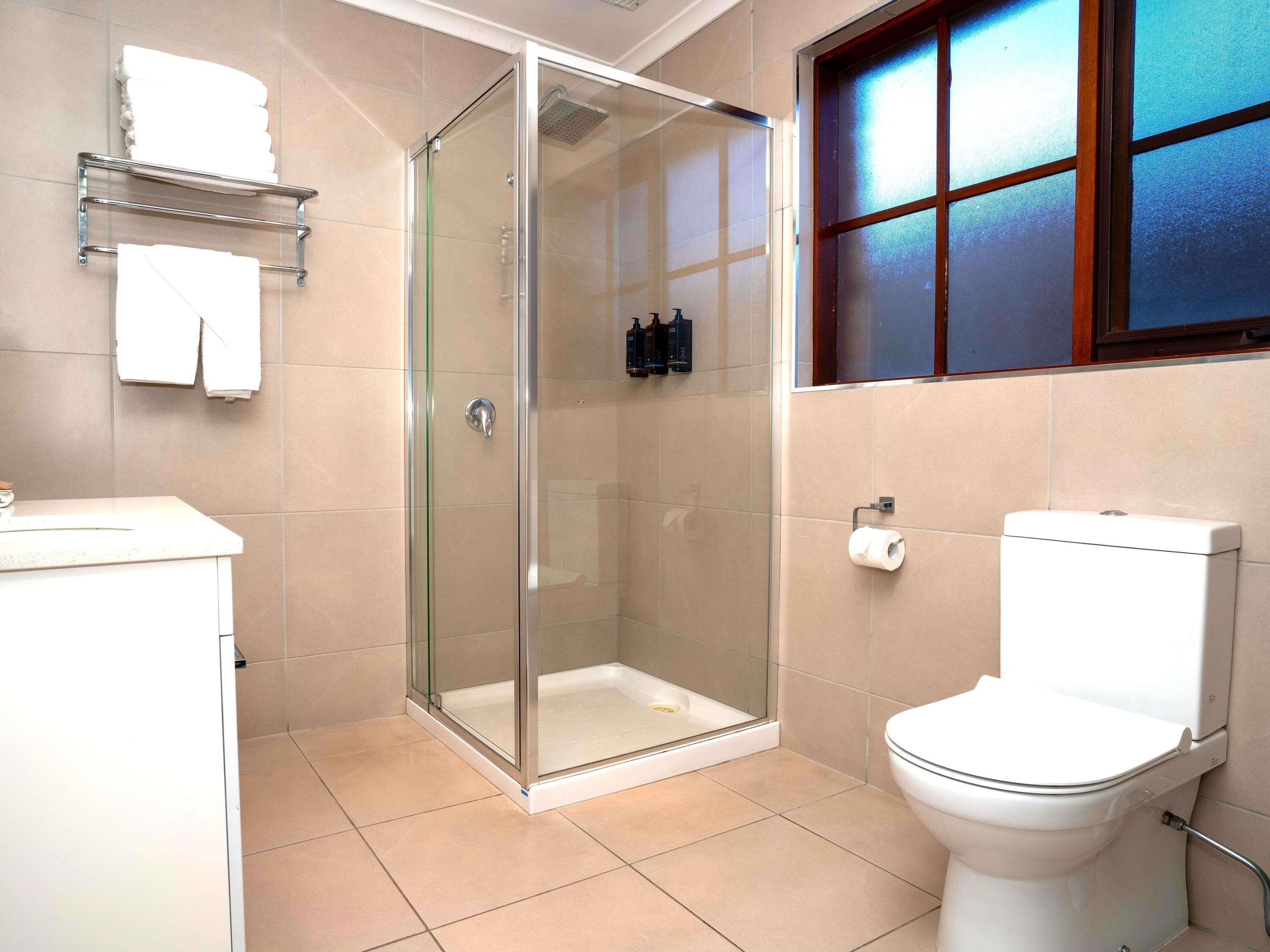 A modern bathroom with a glass-enclosed shower, a toilet, and a sink.
