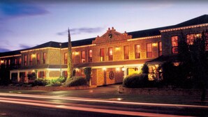 A historic building with a clock tower, illuminated windows, and a well-maintained lawn. - Mercure Port of Echuca (Echuca)