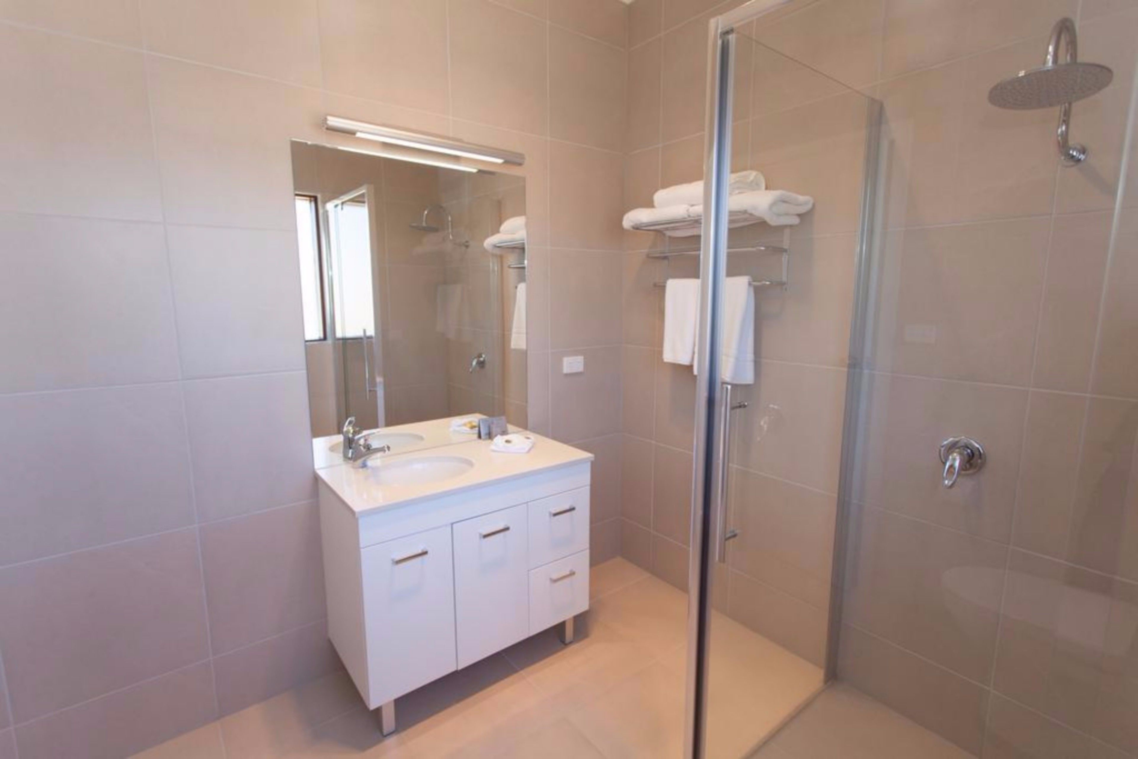 Un baño moderno con cabina de ducha de vidrio, tocador doble y un espejo grande.