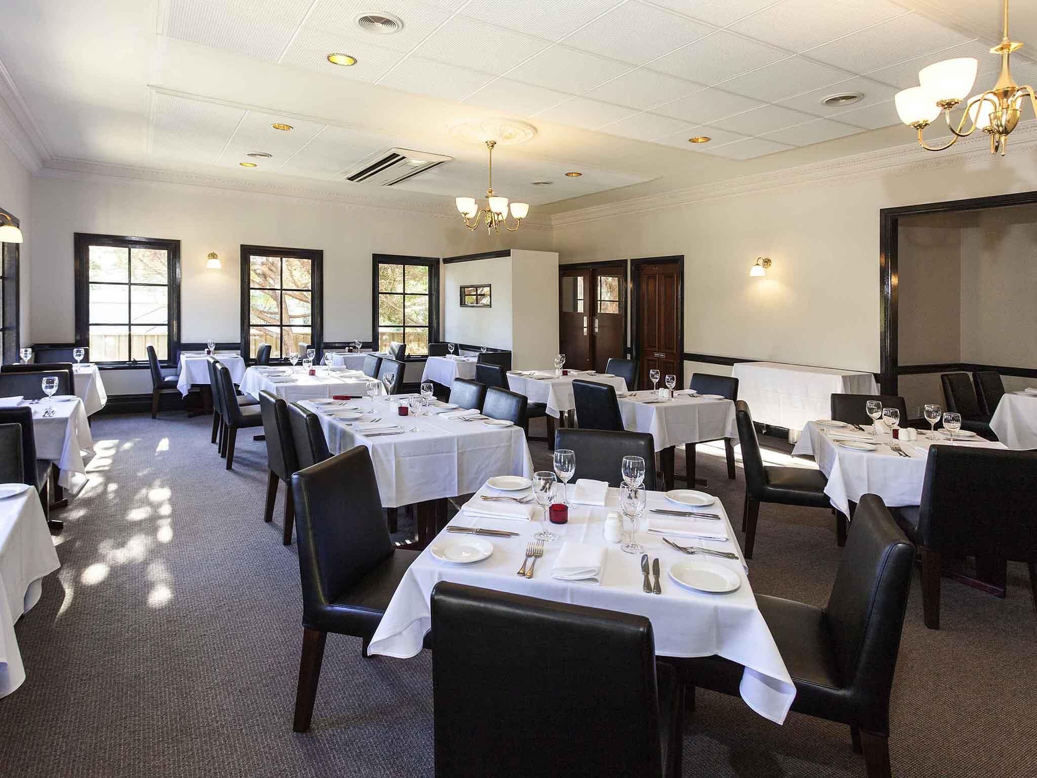 A dining area with multiple tables set for service, chairs, and a chandelier.