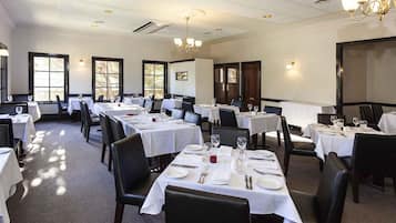 A dining area with multiple tables set for service, chairs, and a chandelier.