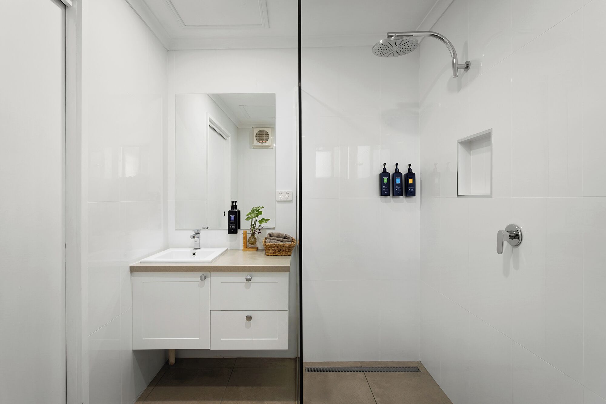 A modern bathroom with a shower, a sink, and a mirror.