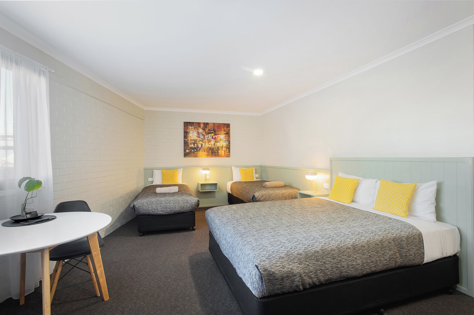 Habitación de hotel con dos camas, un escritorio y una silla.