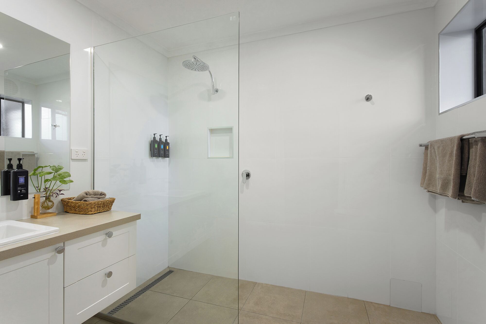 Ein modernes Badezimmer mit einer Duschkabine aus Glas, einem weißen Waschbecken und einem Spiegel.