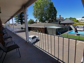 A covered outdoor area with a pool, chairs, and a white car parked nearby. - Townhouse Motor Inn (Horsham)