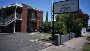Un motel TownHouse con fachada de ladrillo, un porche cubierto y una escalera visible que lleva a la entrada.
