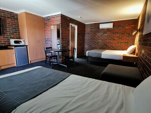 A hotel room with a bed, a desk, a microwave, and a wardrobe. - Townhouse Motor Inn (Horsham)