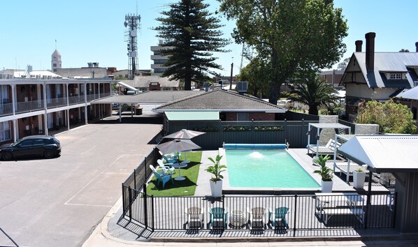 A motel with a swimming pool, outdoor seating, and a fenced parking area. - Townhouse Motor Inn (Horsham)