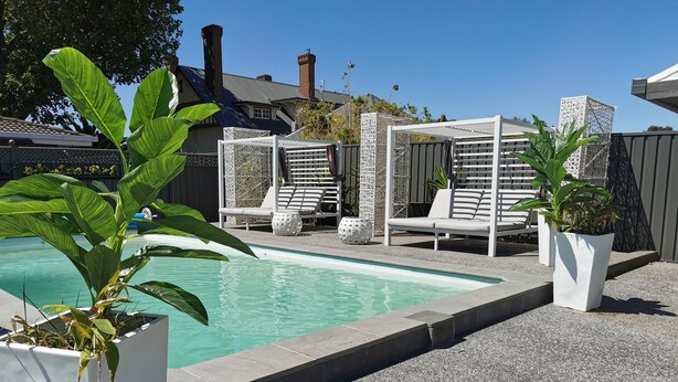 Una piscina con sillones de descanso y macetas.