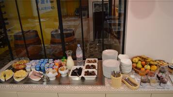 Een buffet met diverse gerechten en dranken, waaronder fruit, yoghurt en een selectie van drankjes.