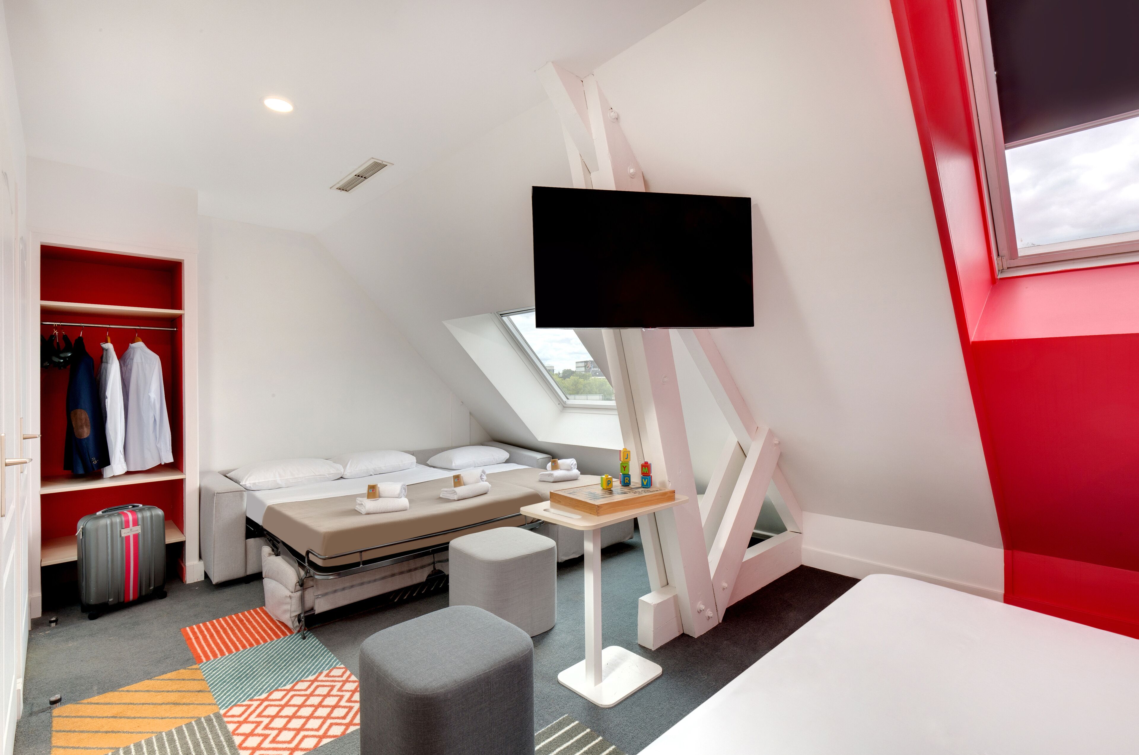 A modern bedroom with a bed, a desk, a TV, and a wardrobe.