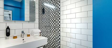 A modern bathroom with a white sink, mirror, and patterned wall tiles.